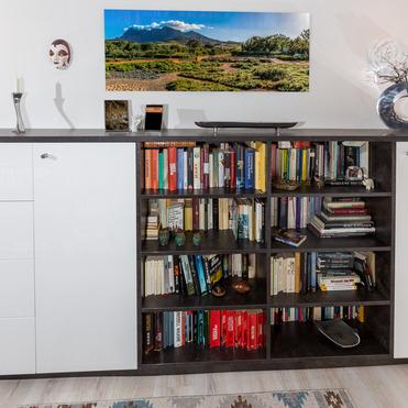 Maßgefertigtes Sideboard von ASADA – Stauraum mit modernem Design Dunkles Sideboard mit offenen Regalen und weißen Fronten, perfekt für die Aufbewahrung von Büchern und Dekoration. Das moderne Möbelstück fügt sich harmonisch in den Wohnraum ein.