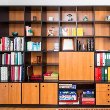 Individuelles Regal mit Holzfronten von ASADA – Vielseitige Stauraumlösung Maßgefertigtes Regal mit schwarzen Kanten und warmen Holzfronten. Es kombiniert offene Fächer, Schubladen und Schränke und bietet Platz für Bücher, Ordner und Gesellschaftsspiele.