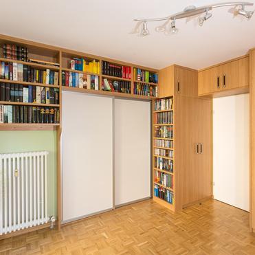 Maßgefertigter Einbauschrank mit Regal von ASADA – Optimale Raumnutzung Eleganter Einbauschrank mit Schiebetüren und integriertem Regal für Bücher. Die warme Holzoptik und die durchdachte Gestaltung schaffen zusätzlichen Stauraum und sorgen für ein harmonisches Raumgefühl.