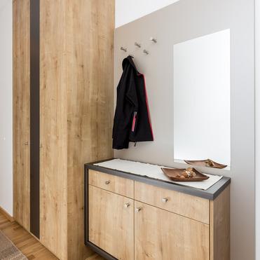 Ein Flur mit einem bodenlangen, maßgefertigten Holzkleiderschrank neben einer passenden Kommode und einem Spiegel.