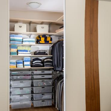 Einblick in einen offenen Kleiderschrank nach Maß, mit Regalen voller gefalteter Handtücher und Kleidung sowie Schubladen.