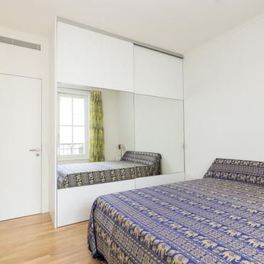 Helles Gästezimmer mit einem großen, spiegelnden Kleiderschrank nach Maß, der das Zimmer optisch vergrößert.