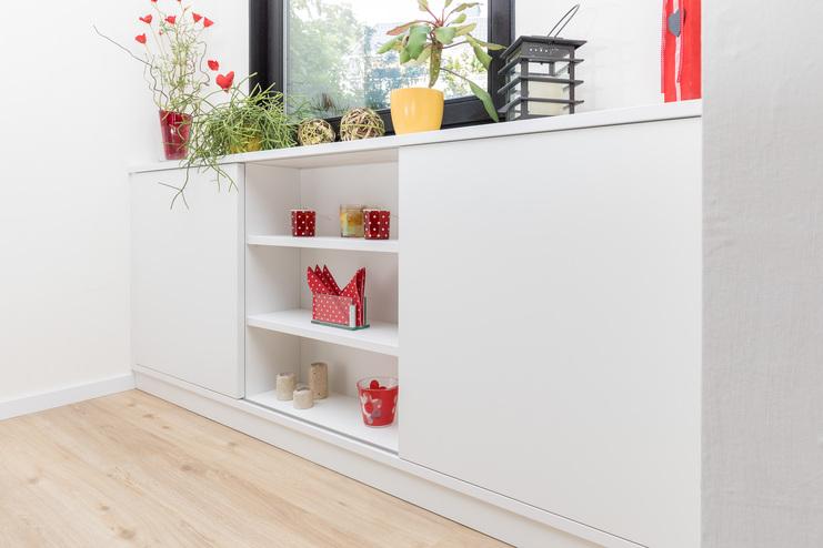 Eingebaute weiße Regale nach Maß mit Dekorationsartikeln in einem hellen Zimmer.