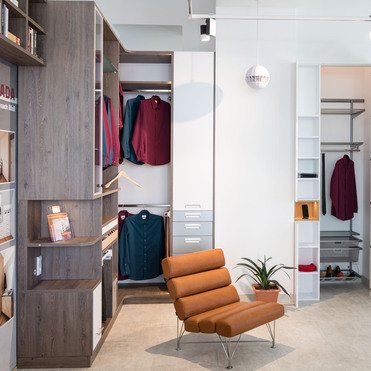 Ein Showroom mit verschiedenen maßgefertigten Möbelstücken, darunter Schränke und Regale, präsentiert in einer offenen Raumaufteilung neben stilvollen Sitzmöbeln und dekorativen Elementen.